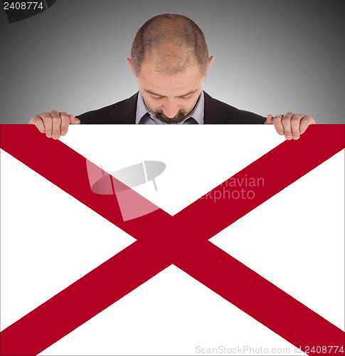 Image of Smiling businessman holding a big card, flag of Alabama