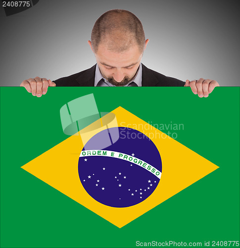 Image of Smiling businessman holding a big card, flag of Brazil