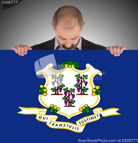 Image of Smiling businessman holding a big card, flag of Connecticut