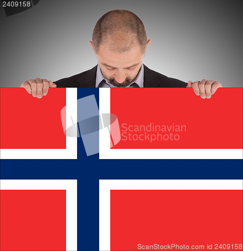 Image of Smiling businessman holding a big card, flag of Norway