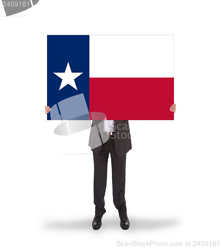 Image of Smiling businessman holding a big card, flag of Texas