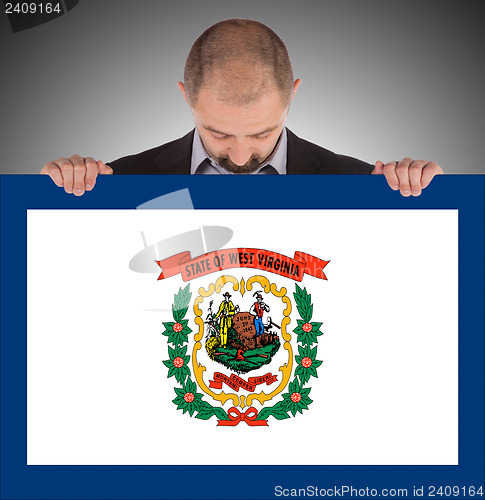 Image of Smiling businessman holding a big card, flag of West Virginia