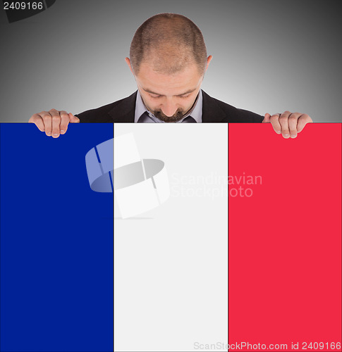 Image of Smiling businessman holding a big card, flag of France