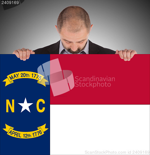 Image of Smiling businessman holding a big card, flag of North Carolina