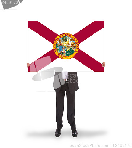 Image of Smiling businessman holding a big card, flag of Florida