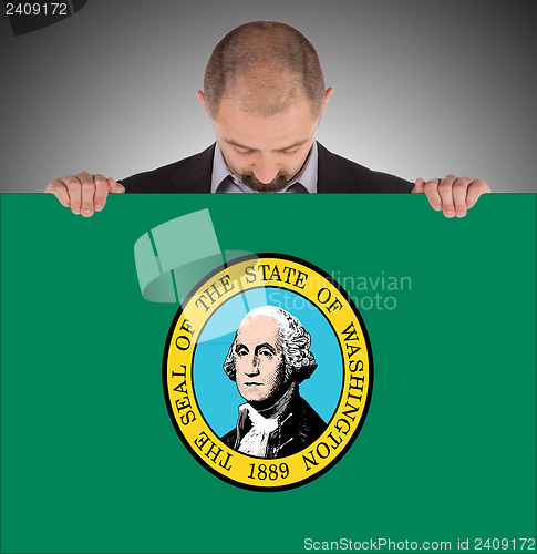 Image of Smiling businessman holding a big card, flag of Washington