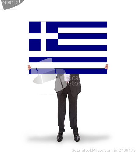 Image of Smiling businessman holding a big card, flag of Greece