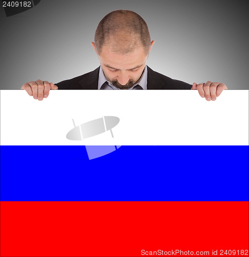 Image of Smiling businessman holding a big card, flag of Russia