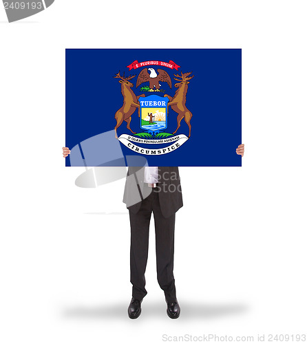 Image of Smiling businessman holding a big card, flag of Michigan