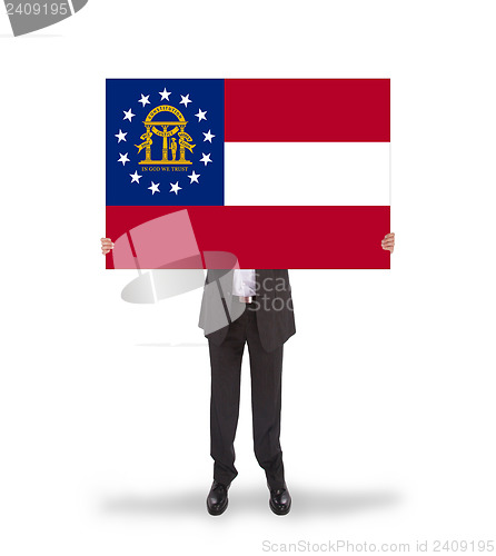 Image of Smiling businessman holding a big card, flag of Georgia