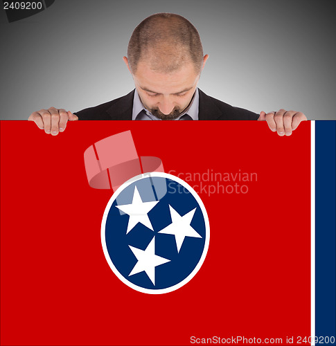 Image of Smiling businessman holding a big card, flag of Tennessee