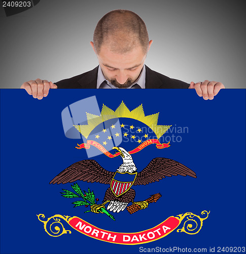 Image of Smiling businessman holding a big card, flag of North Dakota