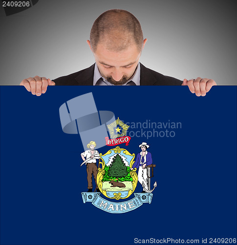 Image of Smiling businessman holding a big card, flag of Maine