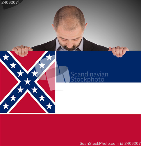 Image of Smiling businessman holding a big card, flag of Mississippi