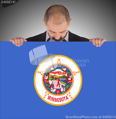 Image of Smiling businessman holding a big card, flag of Minnesota