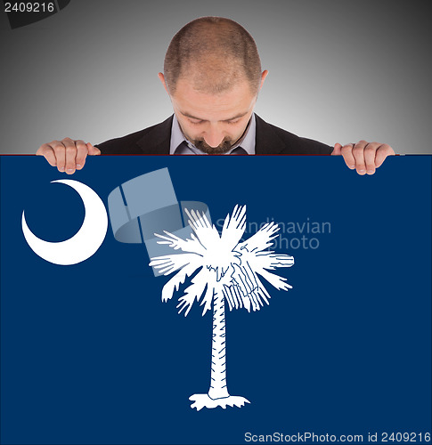 Image of Smiling businessman holding a big card, flag of South Carolina