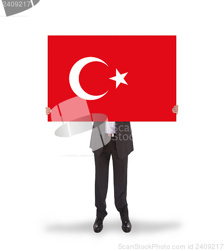 Image of Smiling businessman holding a big card, flag of Turey