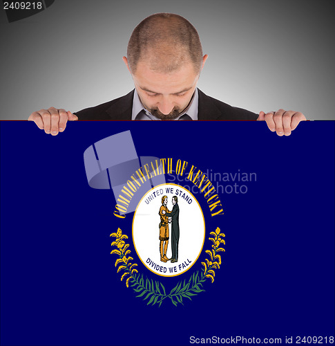 Image of Smiling businessman holding a big card, flag of Kentucky