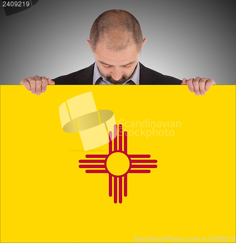 Image of Smiling businessman holding a big card, flag of New Mexico