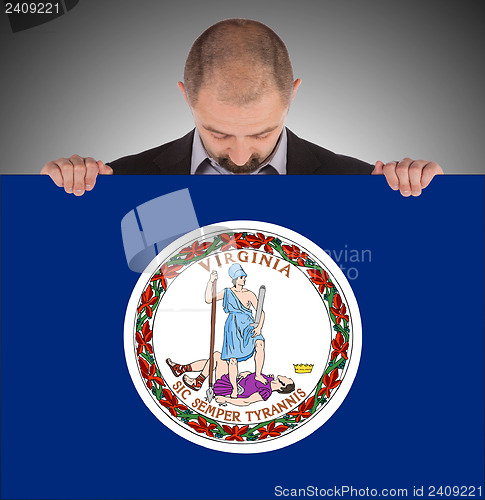 Image of Smiling businessman holding a big card, flag of Virginia