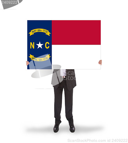 Image of Smiling businessman holding a big card, flag of North Carolina