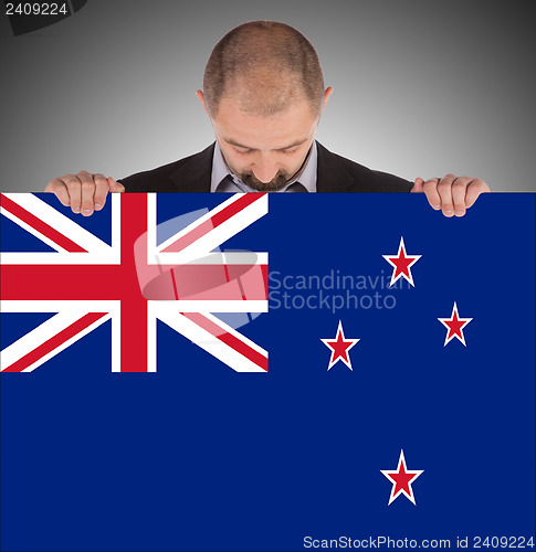 Image of Smiling businessman holding a big card, flag of New Zealand