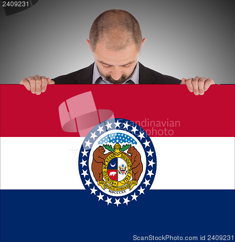 Image of Smiling businessman holding a big card, flag of Missouri