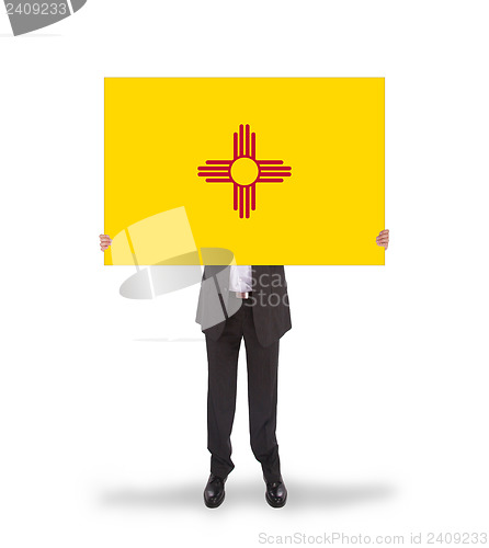 Image of Smiling businessman holding a big card, flag of New Mexico