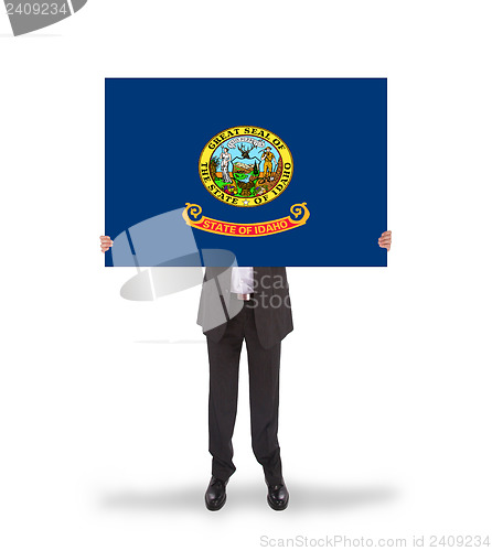 Image of Smiling businessman holding a big card, flag of Idaho