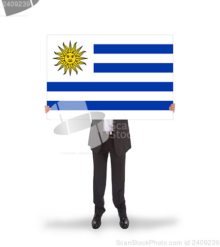 Image of Smiling businessman holding a big card, flag of Uruguay