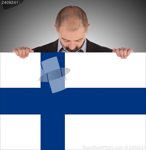 Image of Smiling businessman holding a big card, flag of Finland