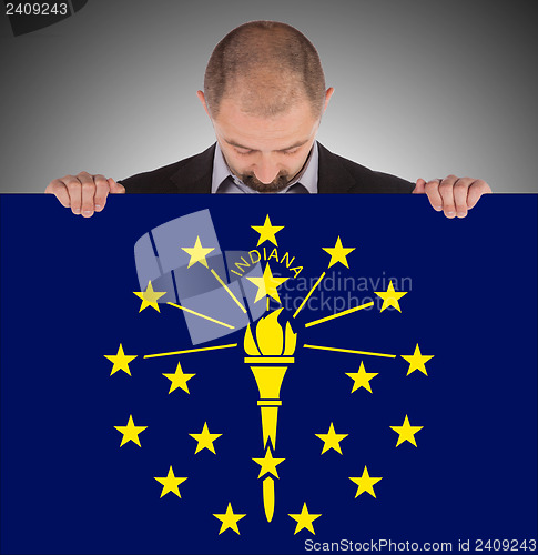 Image of Smiling businessman holding a big card, flag of Indiana