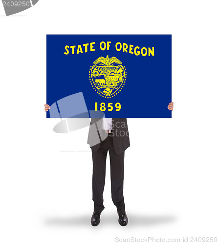 Image of Smiling businessman holding a big card, flag of Oregon