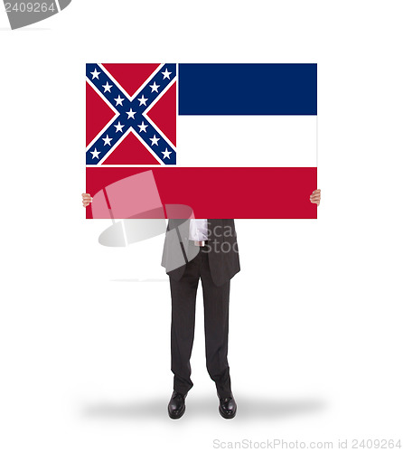 Image of Smiling businessman holding a big card, flag of Mississippi