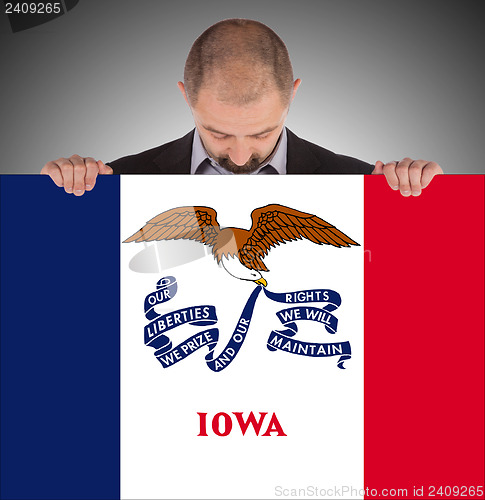 Image of Smiling businessman holding a big card, flag of Iowa