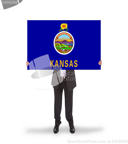 Image of Smiling businessman holding a big card, flag of Kansas