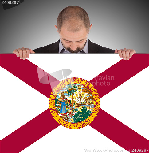 Image of Smiling businessman holding a big card, flag of Florida