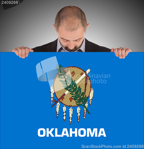 Image of Smiling businessman holding a big card, flag of Oklahoma