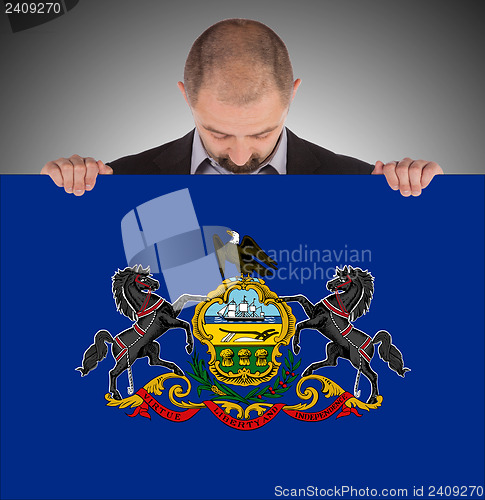 Image of Smiling businessman holding a big card, flag of Pennsylvania