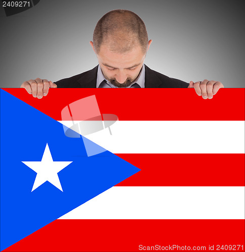 Image of Smiling businessman holding a big card, flag of Puerto Rico
