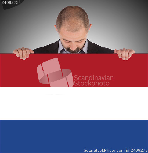 Image of Smiling businessman holding a big card, flag of the Netherlands