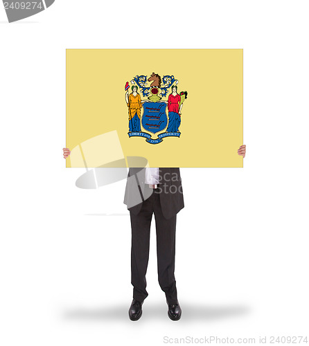 Image of Smiling businessman holding a big card, flag of New Jersey