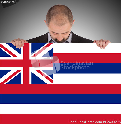 Image of Smiling businessman holding a big card, flag of Hawaii