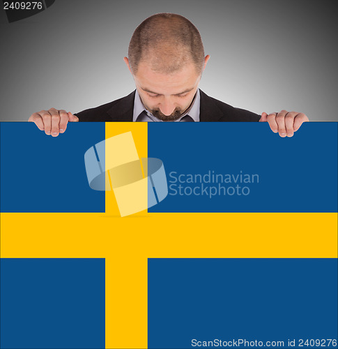 Image of Smiling businessman holding a big card, flag of Sweden