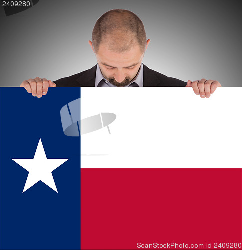 Image of Smiling businessman holding a big card, flag of Texas