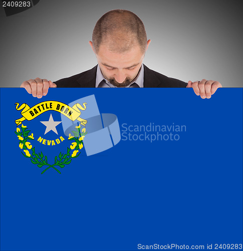 Image of Smiling businessman holding a big card, flag of Nevada