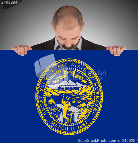 Image of Smiling businessman holding a big card, flag of Nebraska