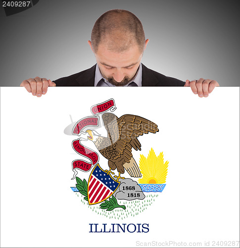 Image of Smiling businessman holding a big card, flag of Illinois