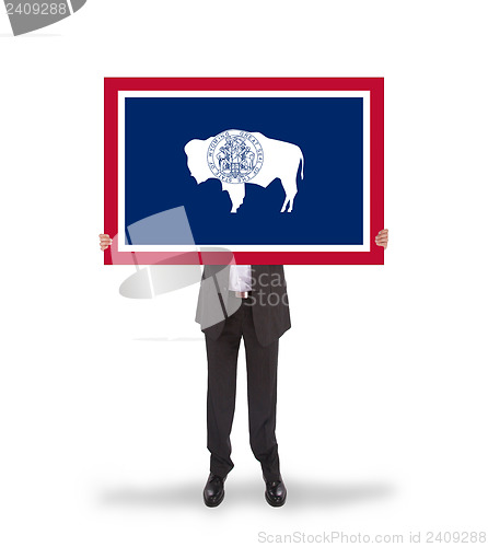 Image of Smiling businessman holding a big card, flag of Wyoming