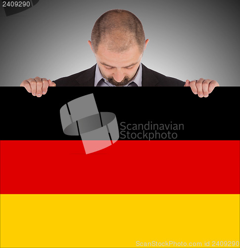 Image of Smiling businessman holding a big card, flag of Germany